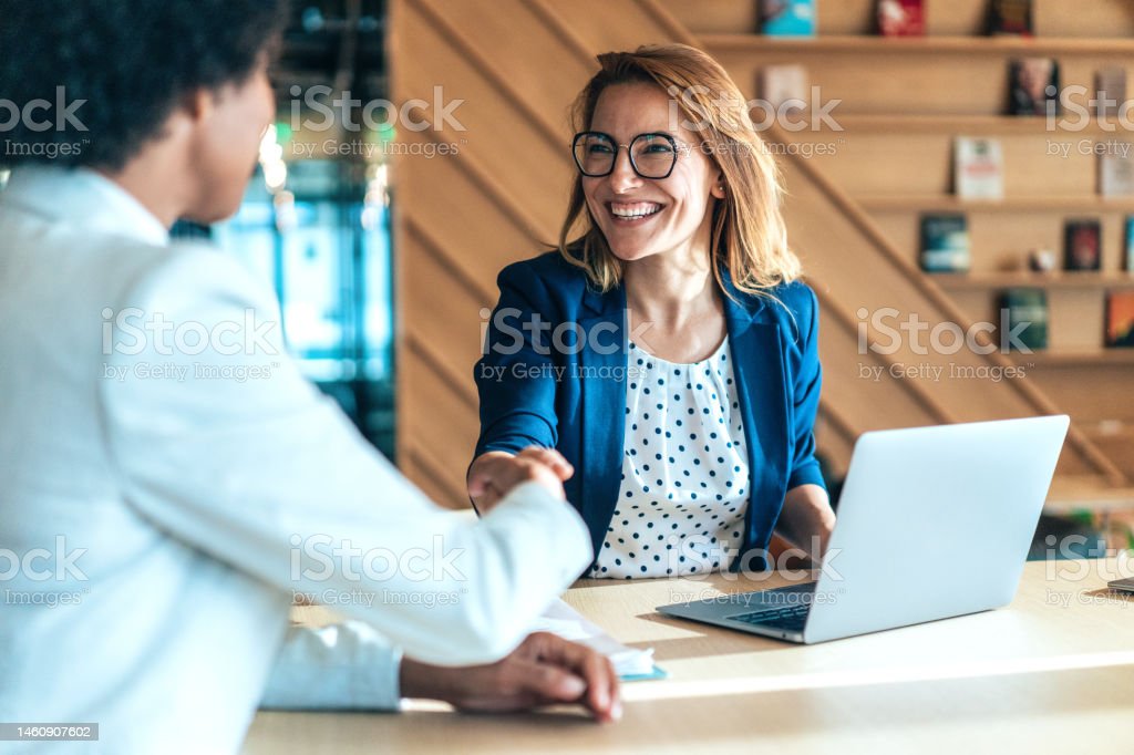 Business people shaking hands in the office. Group of business persons in business meeting. Two entrepreneurs on meeting in board room. Corporate business team on meeting in modern office. Female manager discussing new project with her colleagues. Company owner on a meeting with her employee in her office.